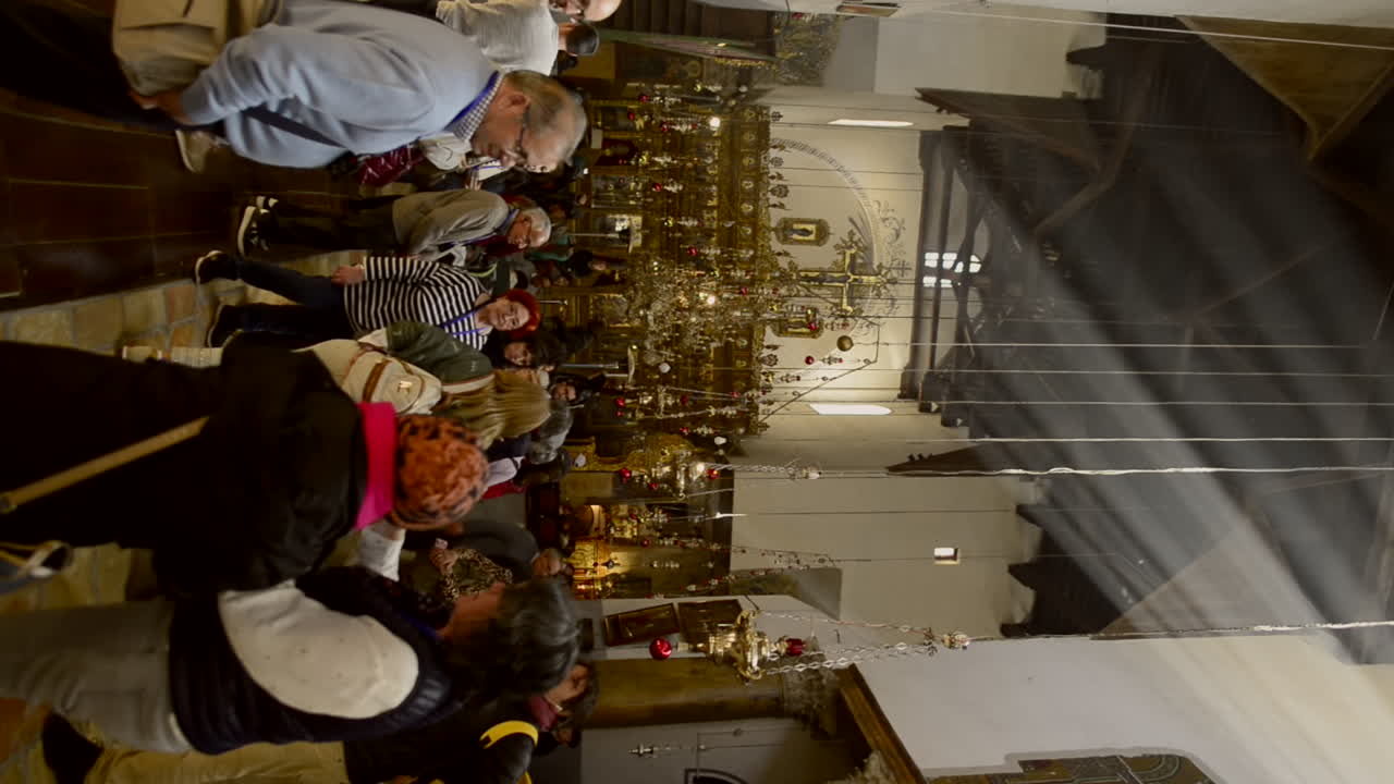 People walk inside catholic church in Jerusalem with natural light beam coming from window. Sacred faith. Vertical