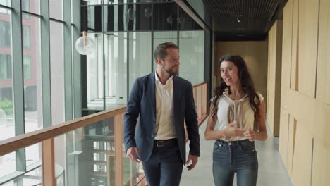 an attractive young businesswoman and a young businessman walking through the corridors of an office building