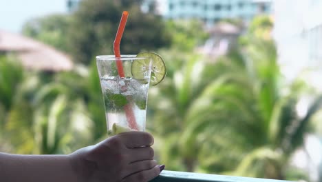 girl-holds-glass-with-frozen-drink-on-hotel-room-balcony