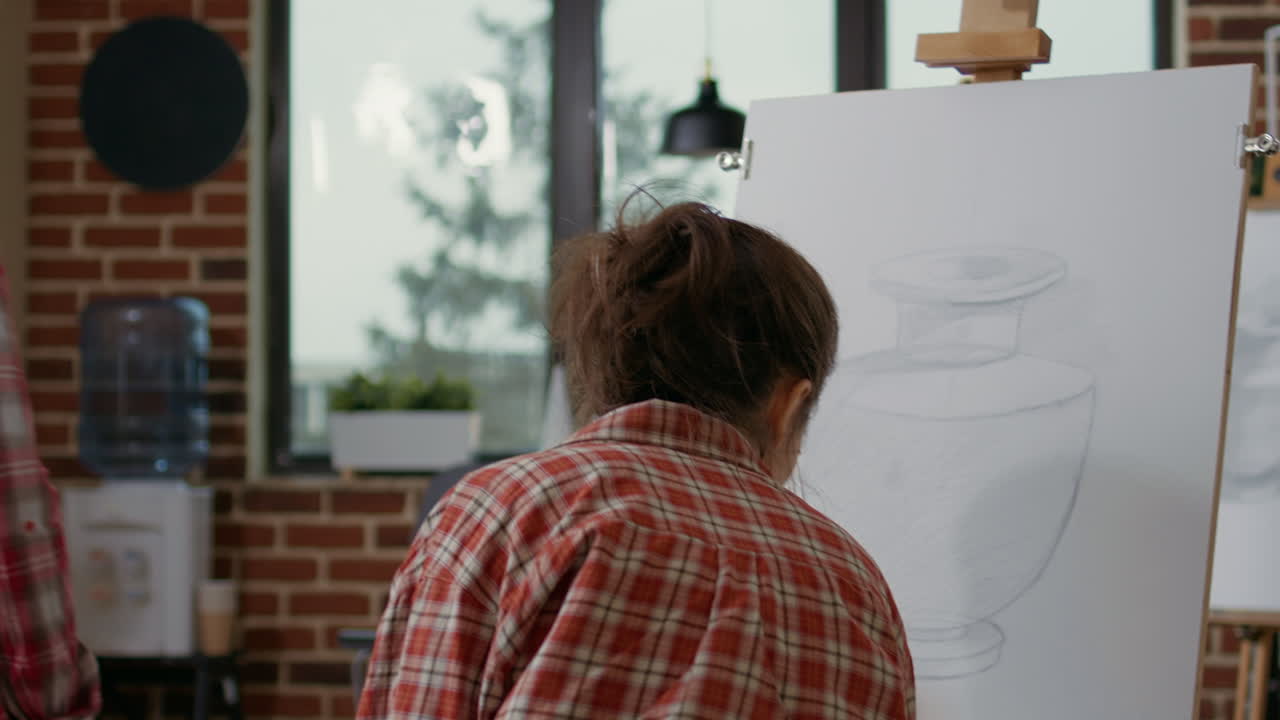 Young woman receiving drawing advice from teacher in art class