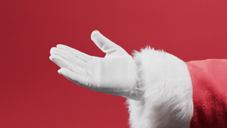video of hand of santa claus in white glove with copy space on red background