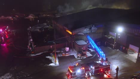 firefighters battling warehouse fire with ladder truck in ste-catherine, québec