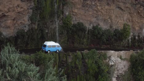 aerial shows a vw-camper van driving through a waterfall, cascada dos anjos, ponta do sol, madeira