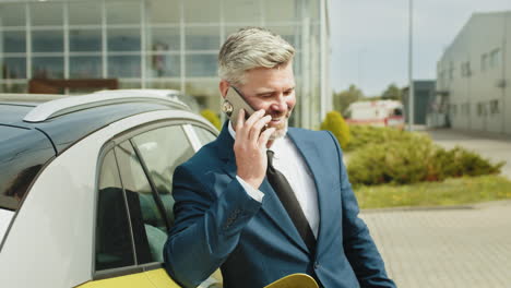 hombre de negocios hablando por teléfono cerca de un coche