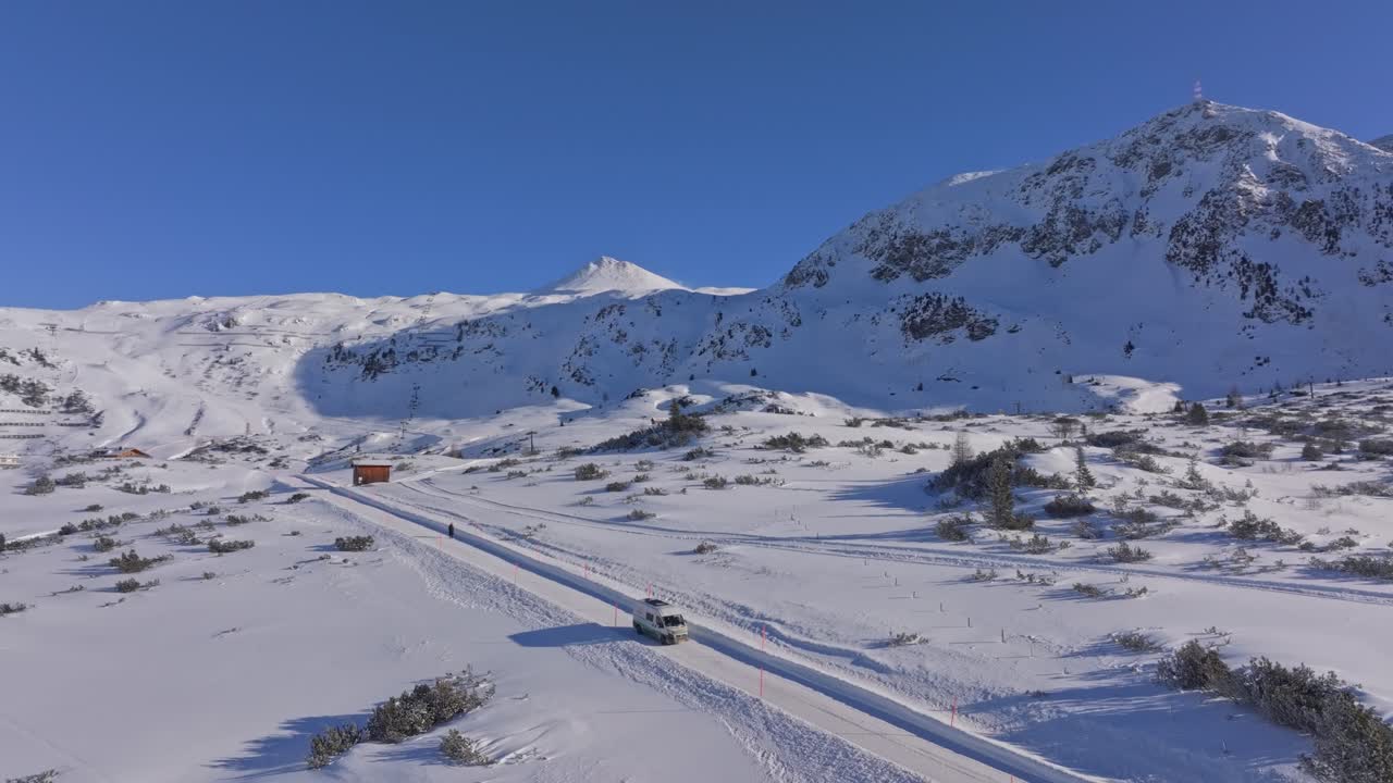 Aerial view of camper van traversing snow-clad streets of Obertauern