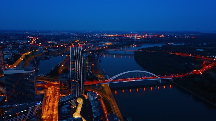 Roads and bridges illuminated with beautiful street lights at dusk time. Vast scenery of Bratislava, Slovakia from drone