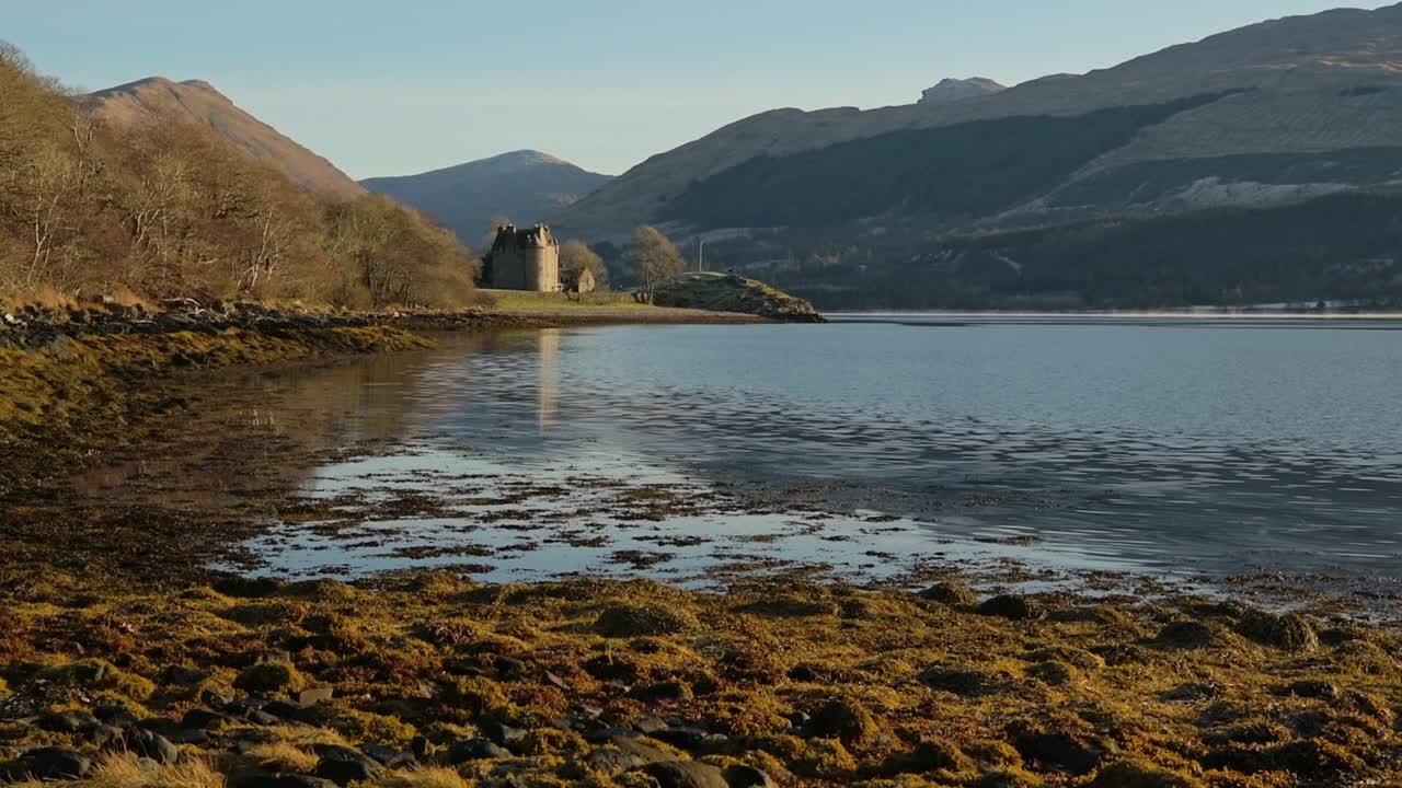 The Rocky Coastline Of Loch Fyne And The Dunderave Castle Surrounded By Mountains Located In Argyll and Bute, Highlands of Scotland. -wide shot