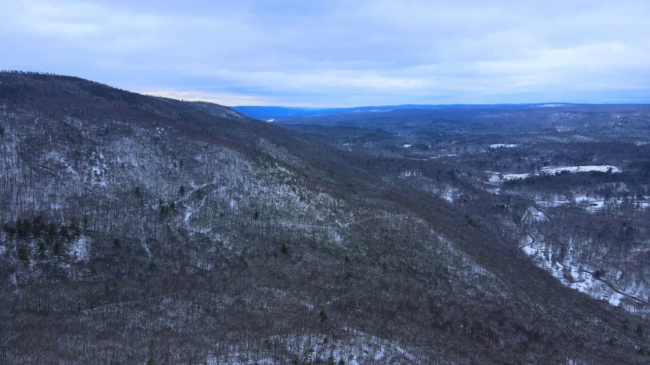 Aerial drone footage of a mountain with hiking trails over a vast valley with snow during winter in the appalachian mountains