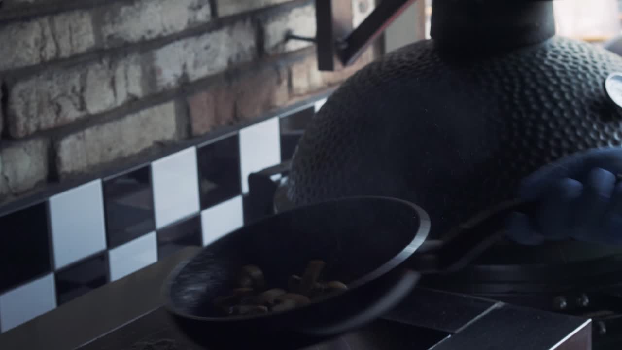 Mushrooms are cooking with alcohol and flame in a frying pan on a kitchen stove. Chef preparing mushrooms with fire