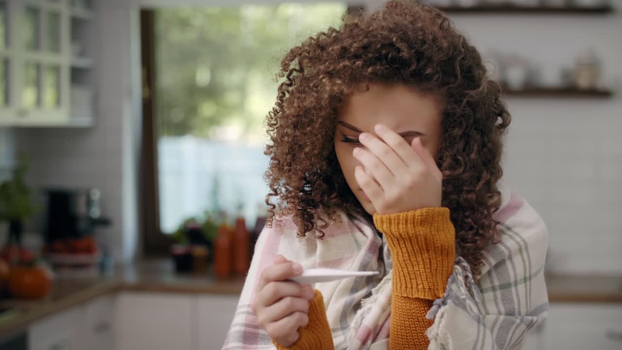 mujer joven preocupada con termómetro comprobando la temperatura/rzeszow/polonia