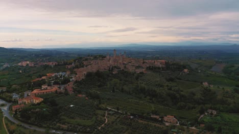 Wunderschöne-Drohnenaufnahmen-Der-Mittelalterlichen-Stadt-San-Gimignano-In-Der-Nähe-Von-Siena,-Ein-Meisterwerk-Historischer-Architektur-In-Der-Idyllischen-Landschaft-Der-Toskana,-Italien,-Mit-Weinbergen,-Hügeln-Und-Olivenbäumen