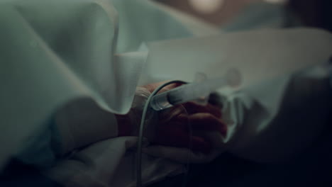 patient hand syringe catheter closeup. unknown man lying in hospital bed.