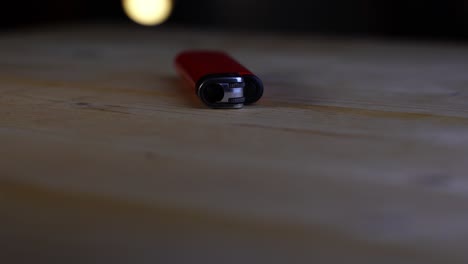 red lighter lies on a table and rotates wooden background