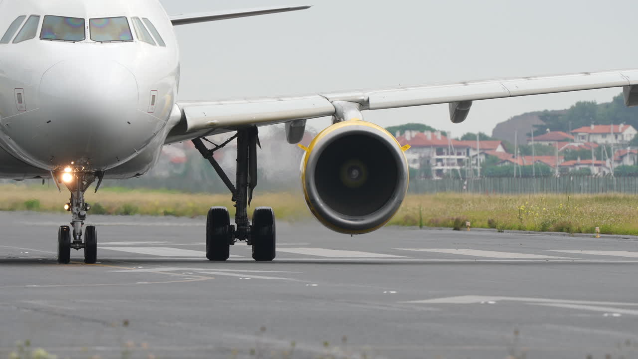 Close front view of commercial jet moving on runway in slow motion with visible turbine rotation