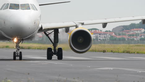 close front view of commercial jet moving on runway in slow motion with visible turbine rotation
