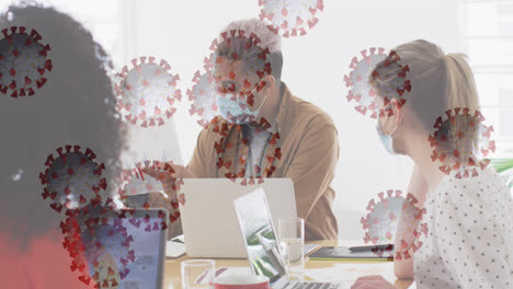 Animation-of-floating-covid-19-cells-with-colleagues-in-office-wearing-face-masks