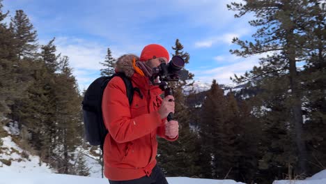 videógrafo profesional usando equipo de invierno usando gimbal y haciendo una caminata ninja a lo largo de un camino cubierto de nieve de invierno en italia