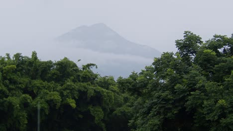la lluvia cae suavemente mientras el volcán acatenango se vislumbra en el fondo en un día nublado y brumoso en antigua, guatemala