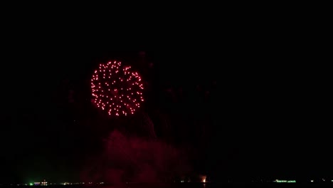 estallido de luces coloridas llenando el cielo nocturno en una playa frente a un popular destino turístico en el sureste de asia durante un festival de fuegos artificiales