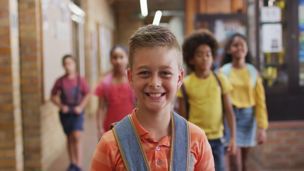retrato de un estudiante caucásico feliz de pie en el pasillo mirando a la cámara