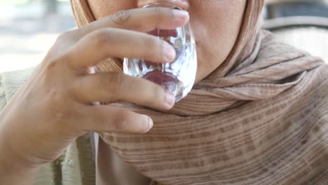 woman in hijab drinking water