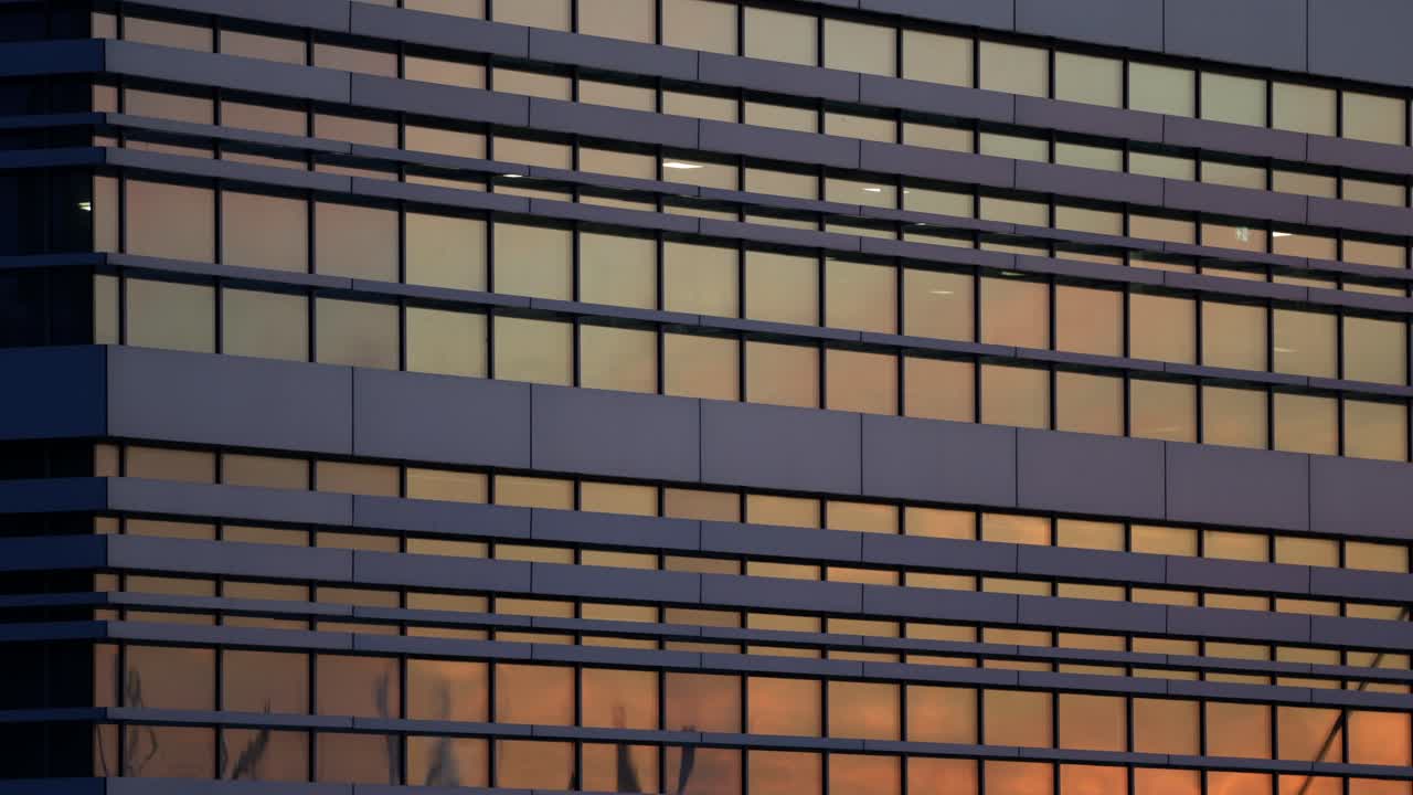 Modern office building reflecting orange sunset light in glass windows