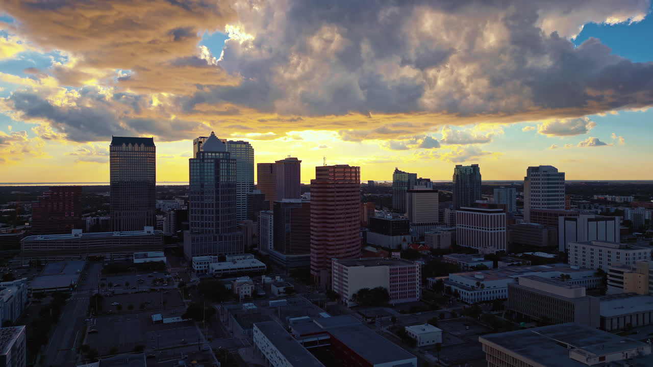 The sun has set in downtown Tampa with massive dramatic clouds of yellow and blue glowing in the sky casting soft warm light on the skyscrapers