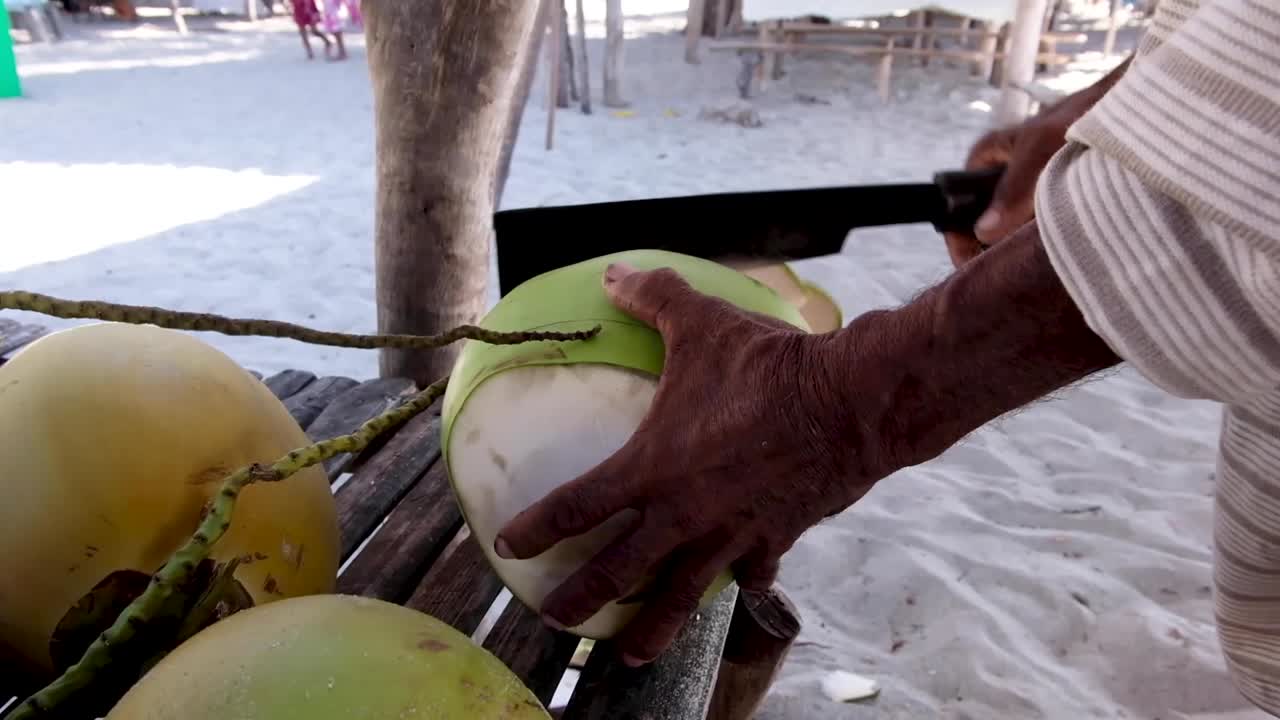 hombre cortando un coco en la playa