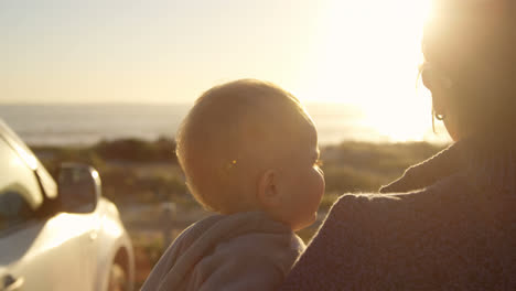 mother holding her baby boy near beach 4k