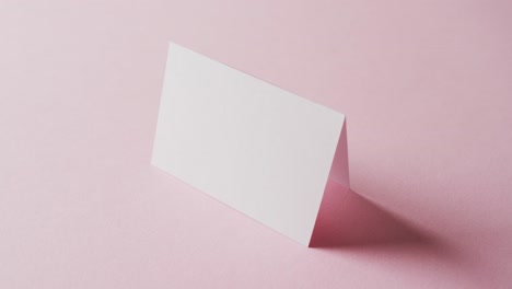 close up of two blank white business cards on pink background, copy space, slow motion