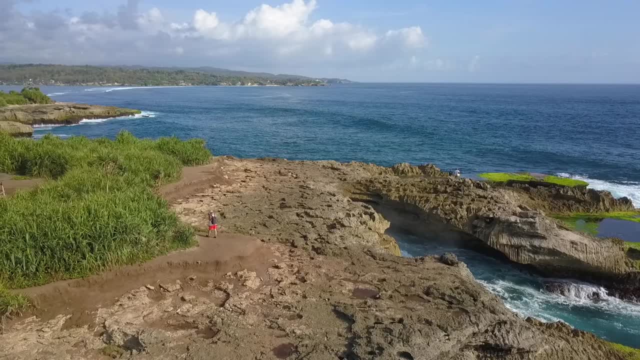 vista aérea más tranquila vuelo volar hacia atrás drone disparó grandes olas del océano rompiendo en las rocas de la lágrima del diablo en lembongan indonesia