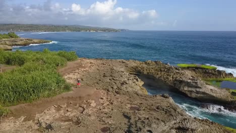 Vista-Aérea-Más-Tranquila-Vuelo-Volar-Hacia-Atrás-Drone-Disparó-Grandes-Olas-Del-Océano-Rompiendo-En-Las-Rocas-De-La-Lágrima-Del-Diablo-En-Lembongan-Indonesia