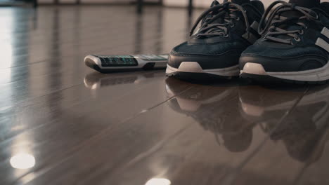 pair of sneakers and a remote control on a wooden floor