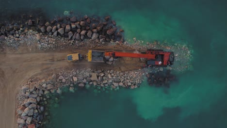 La-Excavadora-Hitachi-EX1200-De-Gran-Alcance-Mueve-Piedras-De-Un-Camión-Al-Mar-Para-Construir-Un-Rompeolas-De-Piedra