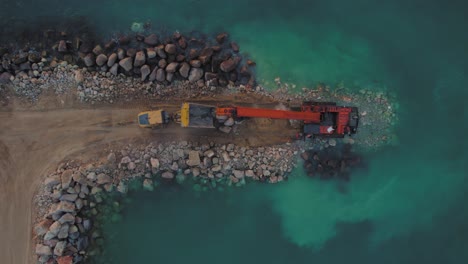 la excavadora hitachi ex1200 de gran alcance mueve piedras de un camión al mar para construir un rompeolas de piedra
