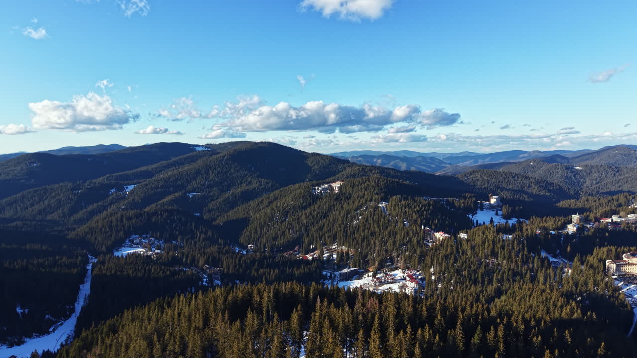 Montagne e foreste in inverno con un cielo azzurro e limpido e nuvole su un paesaggio di giorno.