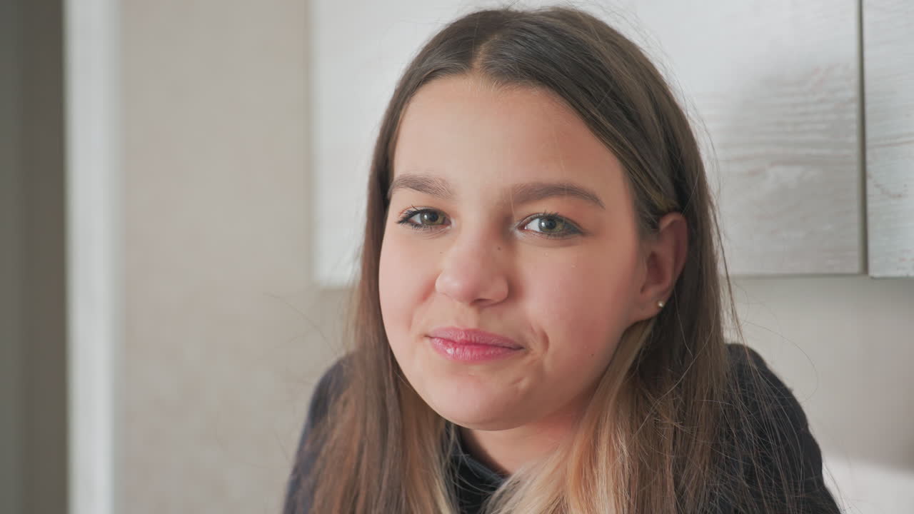 cute kid smiles warmly at camera while seated on kitchen cabinet in modern home setting casual outfit soft natural light creates cozy vibe as sibling reaches into bag to share snack