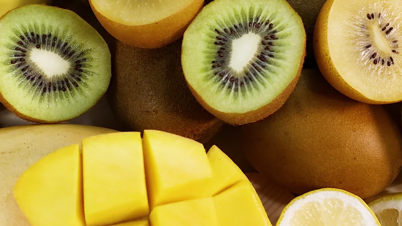 A colorful assortment of sliced and whole fruits including kiwi, mango, banana, and pomegranate.