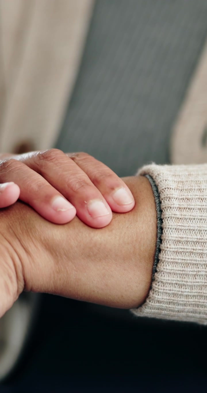 Primer plano de una persona consolando a otra sujetándole el brazo