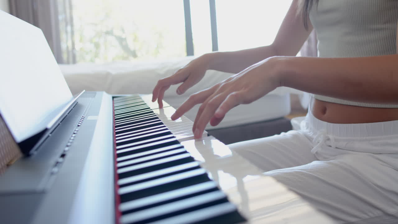 una adolescente caucásica practica el piano, vestida con un traje blanco