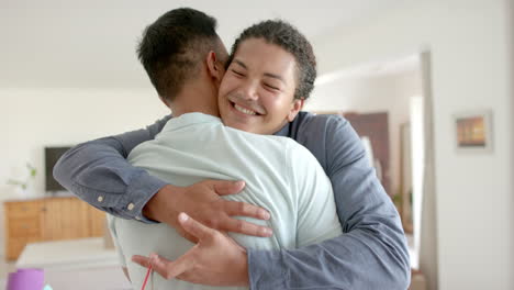 happy diverse gay male couple with keys to new house embracing in living room, slow motion