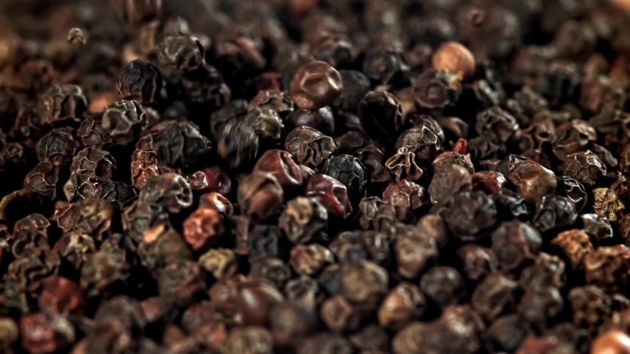 Svarte pepperkorn faller i et nærbilde.