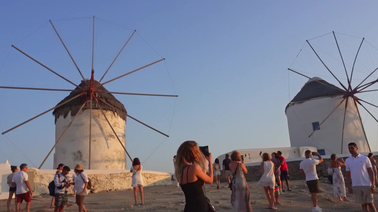 Turisti che visitano gli iconici mulini a vento di Mykonos al tramonto