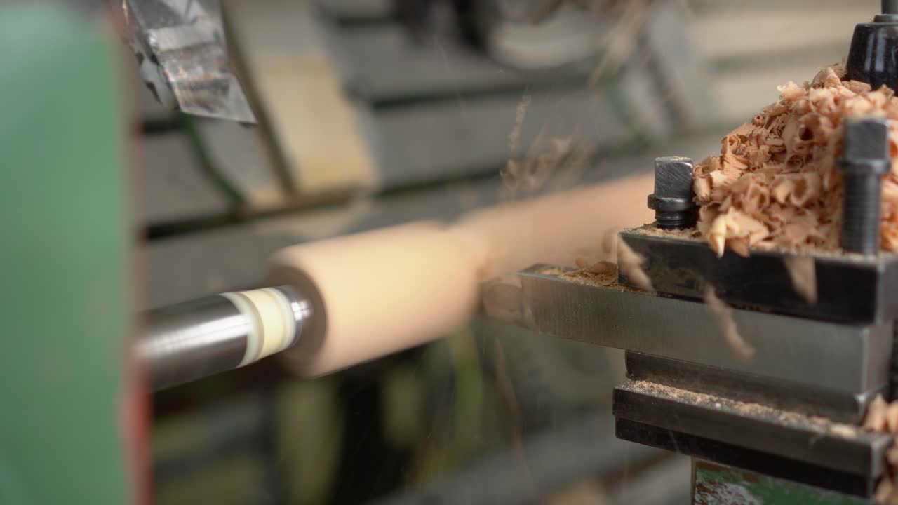 Close-up of wood being shaped on a lathe with shavings flying