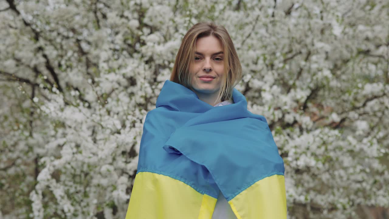 Woman with Ukrainian flag in a spring garden