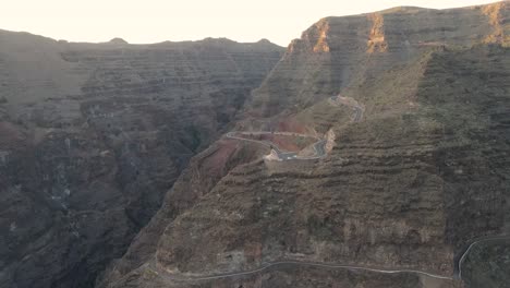 Luftaufnahme-Eines-Weißen-Autos,-Das-Eine-Kurvenreiche-Straße-Auf-Einem-Steilen-Berg-Auf-La-Gomera,-Kanarische-Inseln,-Hinunterfährt