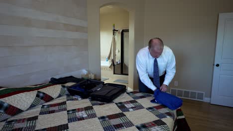 older executive man in a white shirt and tie using packing cubes to organize his luggage