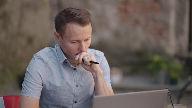 Portrait of a brooding man sitting with a laptop and planning to solve problems and brainstorming