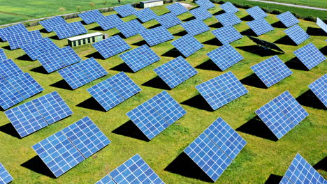 Una-Granja-Solar-Con-Filas-De-Paneles-Solares-Azules-Sobre-Hierba-Verde,-Vista-Aérea