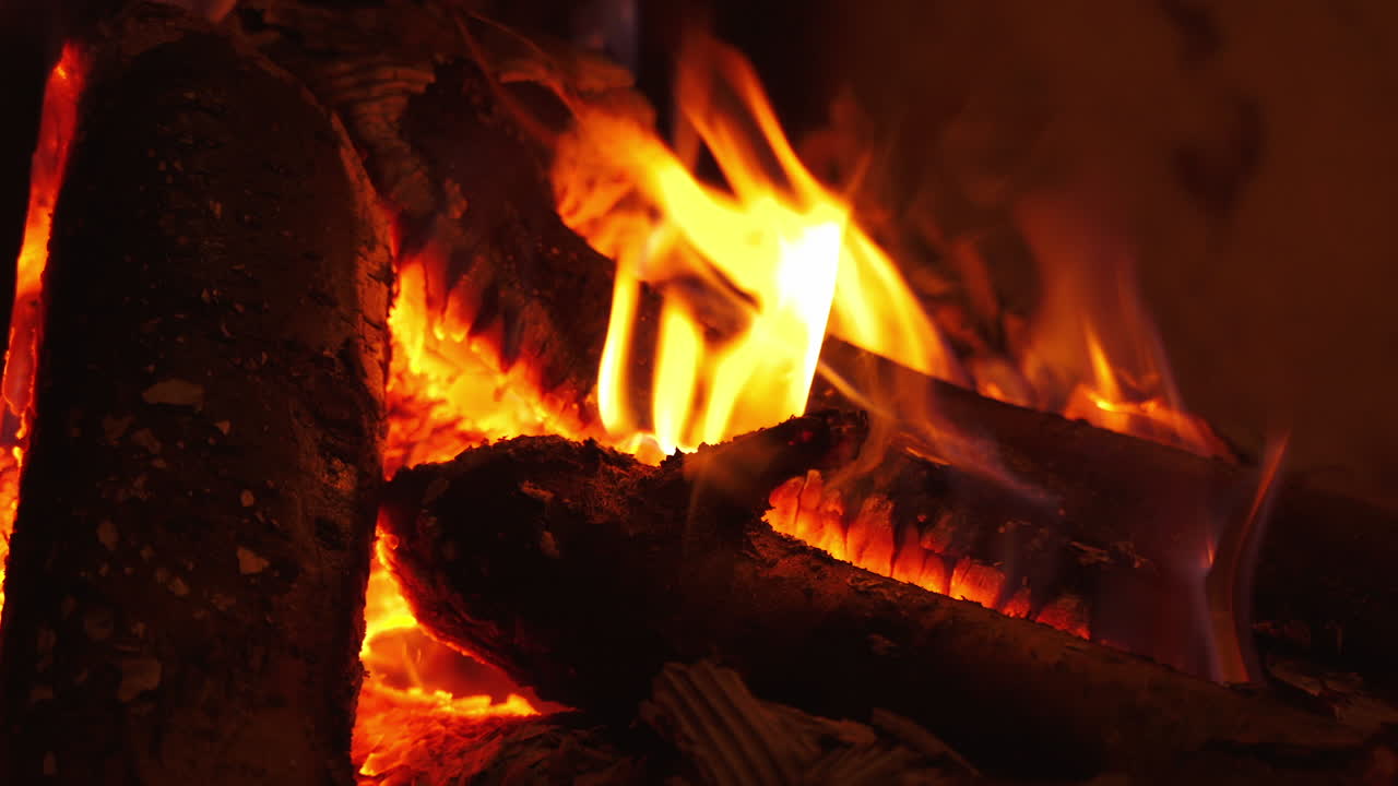 Romantic fireplace. Smoldering logs in hot flame burning in fireplace at home. Motion of fire in wood indoors. Close-up.